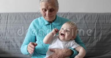 一位年迈的祖母把一个小孙子抱在怀里，和他玩。